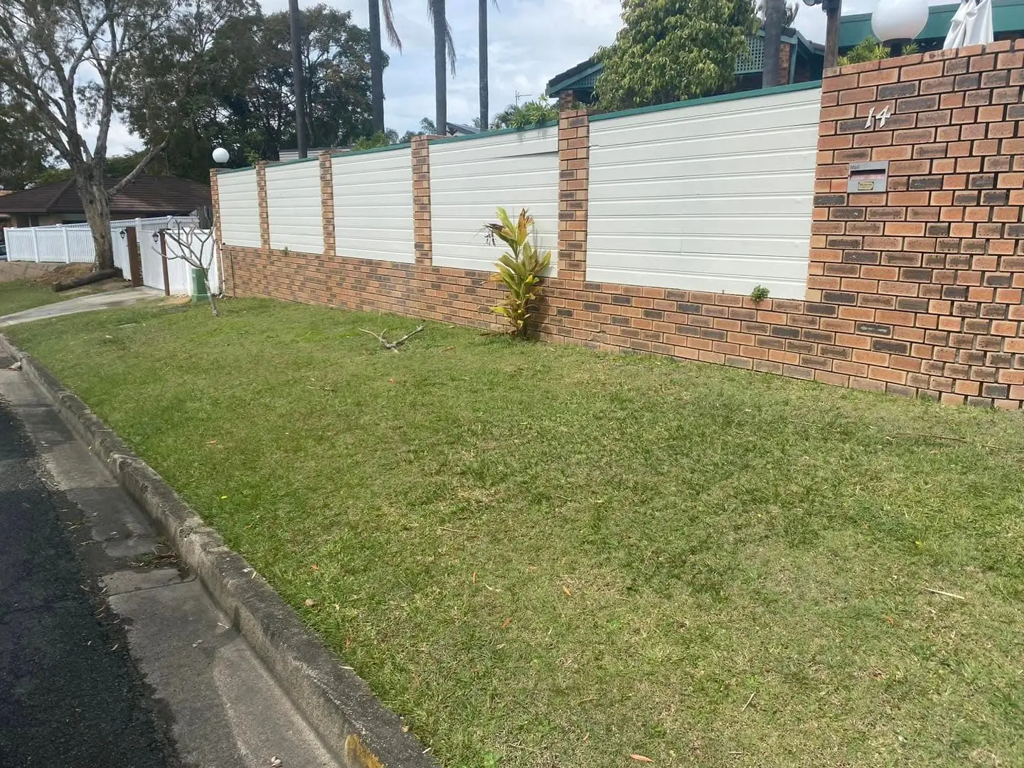 Neat mowed front lawn with brick fence and palms, Molendinar