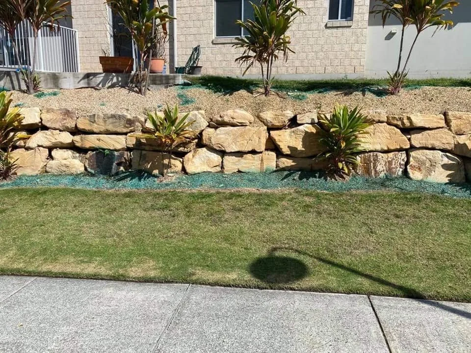 Stone retaining wall garden with tropical plants and lawn, Molendinar